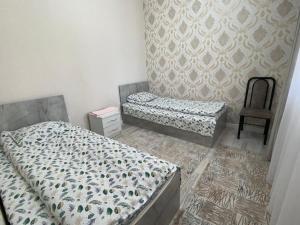 a bedroom with two twin beds and a chair at Жумгал гостевой дом in Chayek
