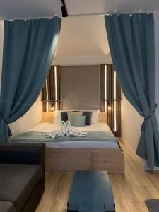 a bedroom with a bed with blue curtains and a couch at Relax House in Praid