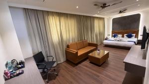 a hotel room with a bed and a couch and a chair at Golden Suites in Bangalore