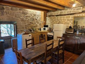 a kitchen with a wooden table and a refrigerator at La maison de Baptiste La Monédière in Chaumeil +6 photos
