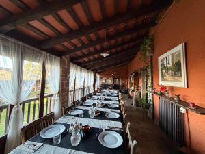 a long row of tables in a room with windows at Mas Cal Sastre in Sant Hilari Sacalm