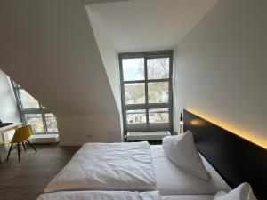 a bedroom with a large white bed and two windows at Printhouse in Münster