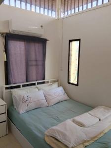 a bedroom with a bed with pink and white pillows at Jonah by The Sea Hideaway Cabin in Ban Sam Maitri