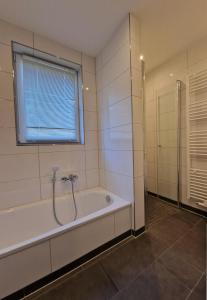 a bathroom with a bath tub and a window at Ferienwohnung Ferienpark Quendorfersee Schüttorf in Schüttorf