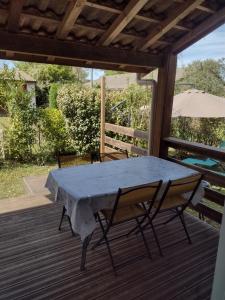 a table on a deck with two chairs and an umbrella at Le petit chalet du Lac Hourtin in Hourtin