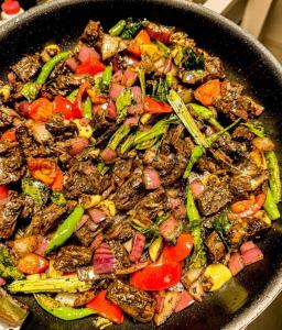 a wok full of food with meat and vegetables at Benthota grand villa in Nakandalagoda