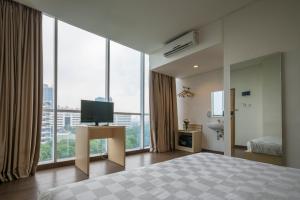 a bedroom with a bed and a tv and large windows at Hotel 88 Grogol Jakarta By WH in Jakarta