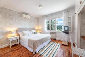 a white bedroom with a bed and a television at Aurora Boutique - Only Adults in Marbella