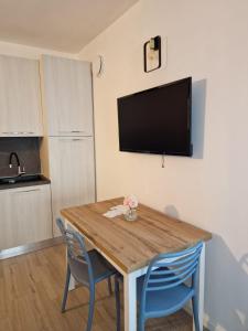 a dining room table with two blue chairs and a flat screen tv at BINARIO 16- new loft in Marone