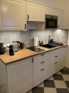 a kitchen with white cabinets and a sink and a microwave at Alpenfels Apartments - Zwieselstein in Sölden