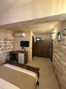 a room with a bed and a tv and a stone wall at Rocinante House in Mardin