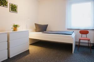 a bedroom with a bed and a red chair at Monteurwohnung Spremberg in Spremberg +1 photo