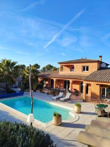 a villa with a swimming pool in front of a house at Villa Catharina in Lorgues