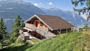 a house on a hill with mountains in the background at Chalet Wildi Horu OG in Niedergesteln