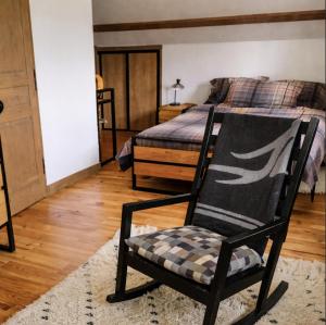 a black rocking chair in a bedroom with a bed at Villa MYRTILLE classée 4 étoiles meublé de tourisme - Vue montagne, terrasse, jardin, 8 pers in Murat-le-Quaire