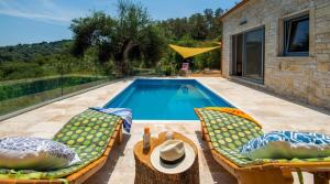 a swimming pool with two lounge chairs next to a house at Lucié in Argyrátika