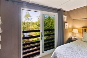 a bedroom with a large sliding glass door with a view at Little Longbow Lakefront Chalet in Becket
