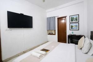 a bedroom with a bed with a flat screen tv on the wall at Mauryan Express I Hotel Malviya Nagar in New Delhi +11 photos