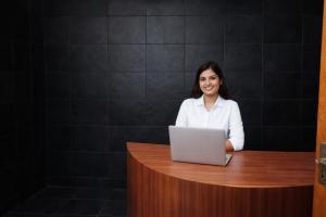 a woman sitting at a desk with a laptop at Mauryan Express I Hotel Malviya Nagar in New Delhi