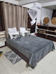a bedroom with a bed with a gray comforter at Le Goyav' appart avec piscine et jacuzzi au Vauclin in Le Vauclin +27 photos
