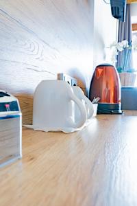 a white coffee cup sitting on the floor next to a toaster at Hotel Casa Maria in Halblech