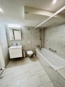 a bathroom with a tub and a toilet and a sink at Gemütliches Wohnung für Familien und Gruppen in Küblis