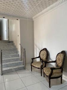 two chairs sitting in a room with stairs at Dar Tozeur in El Oudiane-Degache +4 photos