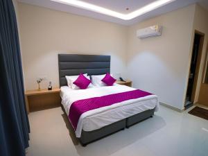 a bedroom with a large bed with purple pillows at K Hotels by SYN in Bangalore