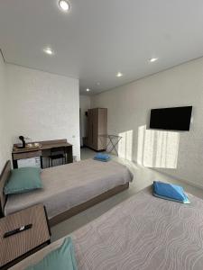 a bedroom with a bed and a desk and a tv at Welcome Hotel in Kostanay