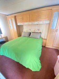a bedroom with a green bed in a room at PD Wonderwall Caravan, Direct beach access & Beds made on arrival & GCH in Ingoldmells