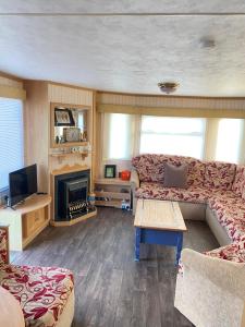 a living room with a couch and a fireplace at PD Wonderwall Caravan, Direct beach access & Beds made on arrival & GCH in Ingoldmells