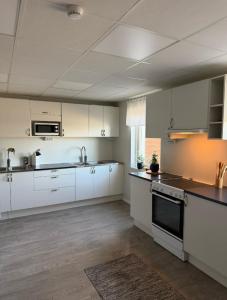 a kitchen with white cabinets and a black and white appliances at Bryggans Vandrarhem in Västervik