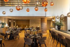 a restaurant with tables and chairs and pendant lights at Golden Age Athens Hotel in Athens