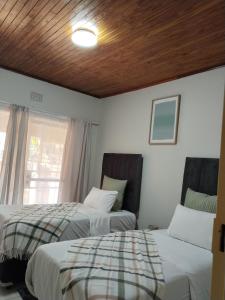 a bedroom with two beds and a window and a ceiling at Five-Bedroom House at 27 Baobab Avenue, Birchleigh, Kempton Park, Backup Power Supply in Kempton Park