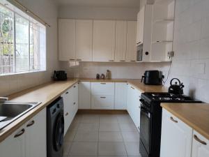 a white kitchen with white cabinets and black appliances at Five-Bedroom House at 27 Baobab Avenue, Birchleigh, Kempton Park, Backup Power Supply in Kempton Park