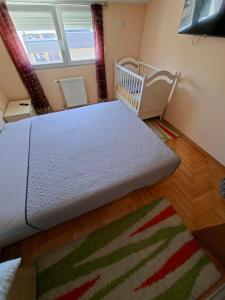a bedroom with a bed and a crib and a rug at Index Apartman in Banja Luka