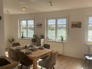 a dining room with a table and chairs and windows at Haus Fährblick in Rees