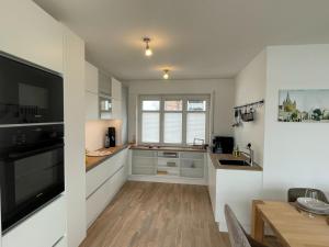 a kitchen with white cabinets and a sink and a table at Haus Fährblick in Rees +17 photos