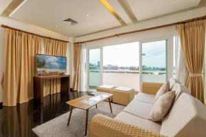 a living room with a white couch and a large window at Phunawa Resort Phuket Karon Beach in Karon Beach