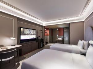 a hotel room with two beds and a flat screen tv at Mercure Beijing Zhongguancun in Beijing