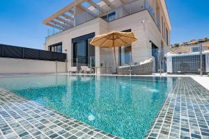 a swimming pool with an umbrella next to a house at רויאל טווינס בוטיק in Safed