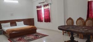 a bedroom with a bed and a table and red curtains at Hotel & Bothgaya Waterpark in Bodh Gaya