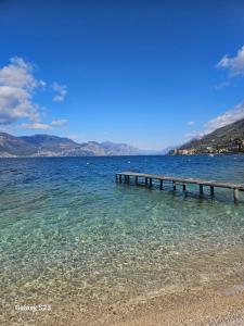 a pier in the water next to a beach at Appartamento Torri del Benaco in Torri del Benaco