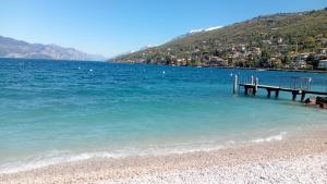 a dock in the water next to a beach at Appartamento Torri del Benaco in Torri del Benaco