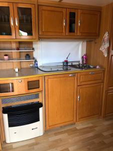 a kitchen with wooden cabinets and a stove top oven at Caravane revisité in Pleslin-Trigavou +7 photos