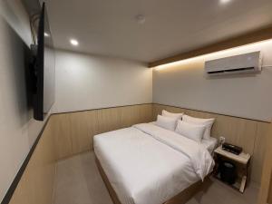 a small bedroom with a white bed and a tv at Latree Hotel in Seoul
