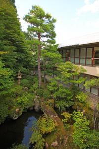 a garden with a pond in front of a building at Shiki Resort Hida Takayamaso in Takayama