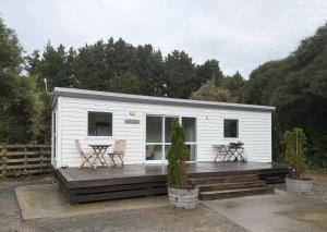 a small white cabin with a wooden deck at BENROSE FARM COTTAGES in Wellington