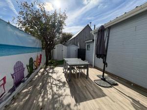 a wooden deck with a table and an umbrella at La cabine de plage in Batz-sur-Mer +15 photos
