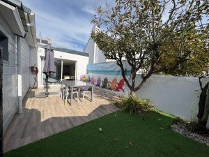 a patio with a table and a tree in a yard at La cabine de plage in Batz-sur-Mer